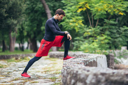 Man runner training. Male athlete stretching muscles at the park. Healthy, fitness, wellness...