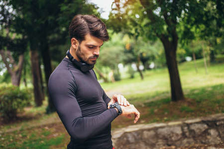 Young sportsman listening to music while doing exercising in the park. Fitness, sport, lifestyle...