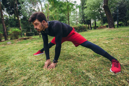 Man runner training. Male athlete stretching muscles at the park. Healthy, fitness, wellness lifestyle. Sport, cardio, workout conceptの写真素材