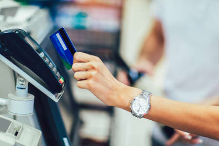 Hand of customer paying with contactless credit card with NFC technology.