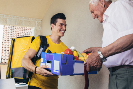 Young male volunteer delivering shopping to senior man. Donation