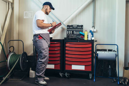 Man writing on a clipboard in a garage.の写真素材