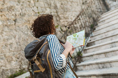 Woman tourist walking on the street in european old city using map.