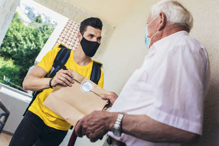 Young male volunteer delivering shopping to senior man. Donationの写真素材