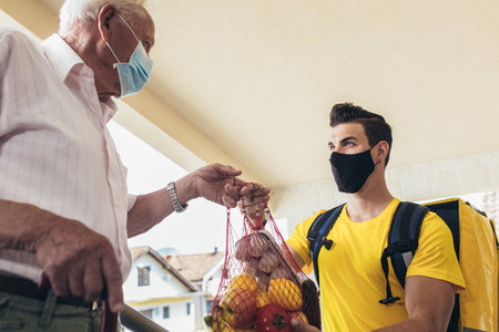 Young male volunteer delivering shopping to senior man. Donationの写真素材