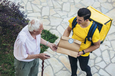 Young male volunteer delivering shopping to senior man. Donationの写真素材