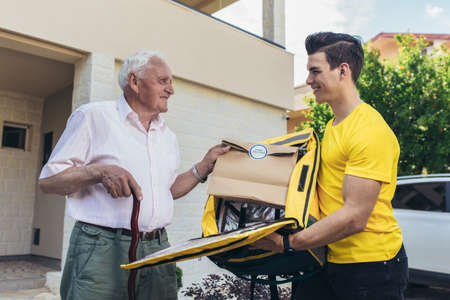 Young male volunteer delivering shopping to senior man. Donationの写真素材