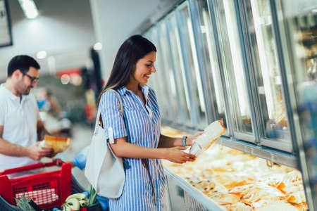 Happy couple buying frozen food in store or supermarketの写真素材