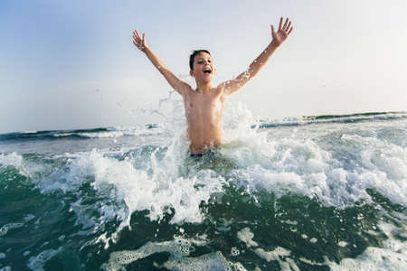 Happy child playing in the sea. Kid having fun outdoors. Summer vacation and healthy lifestyle concept. Selective focusの写真素材