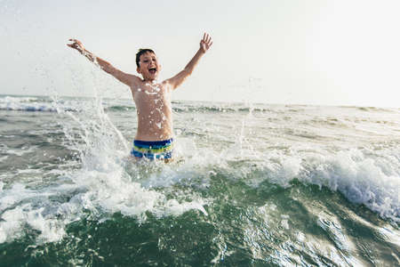 Happy child playing in the sea. Kid having fun outdoors. Summer vacation and healthy lifestyle concept. Selective focusの写真素材