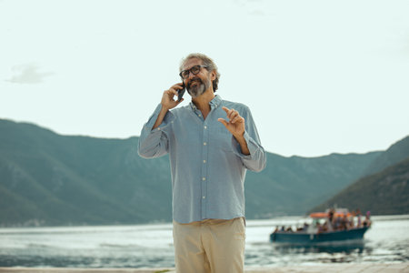 Mature man talking on the smartphone on the marina.の写真素材