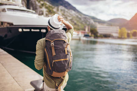 Young man walking by the harbor of a touristic sea resort with boats on backgroundの写真素材