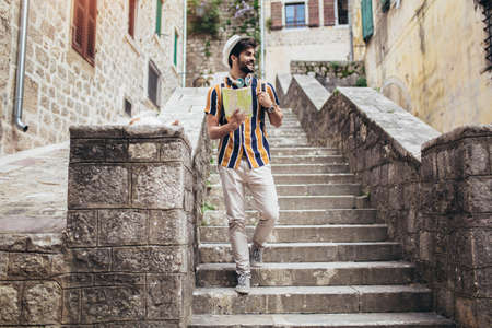 Happy tourist with backpack is making travel across city uses a map for orientation.の写真素材
