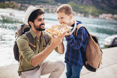 Father and son eating pizza. Happy, joyful family.の写真素材