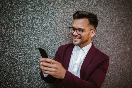 Happy handsome businessman using mobile phone outdoorの写真素材