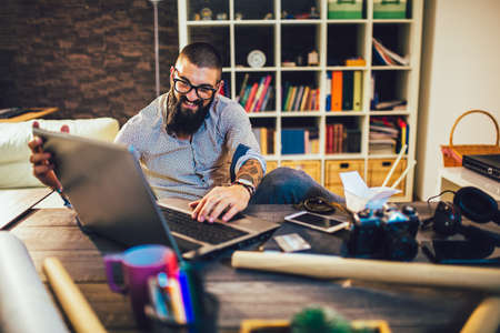 Young man working on his laptop computer at homeの写真素材