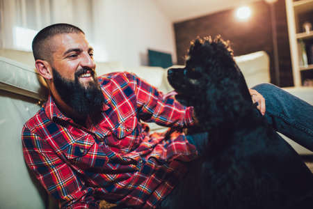 Best Friend Concept. Handsome man with cute dog at home.の写真素材