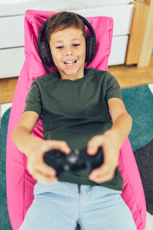 Little boy with gamepad playing video game at home