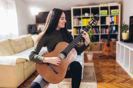 Teen girl practicing some new sound on a guitar at home