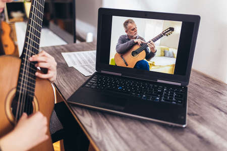 Girl playing guitar with computer, learn to play with an online courseの写真素材