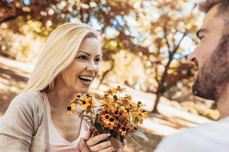 Loving young couple on a date with flowers in the parkの写真素材