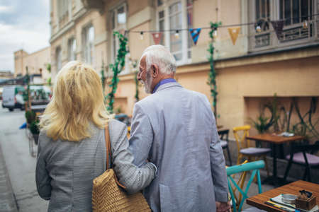 Mature married couple are walking through a city together.