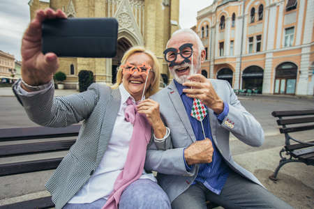 Happy senior couple taking a selfie together in the city and having fun.の写真素材