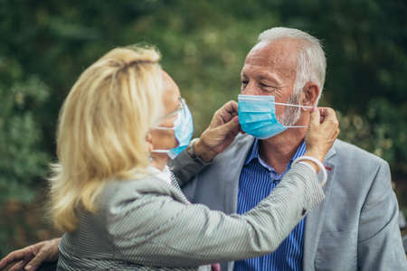 Senior couple wearing protective face masks outdoorsの写真素材