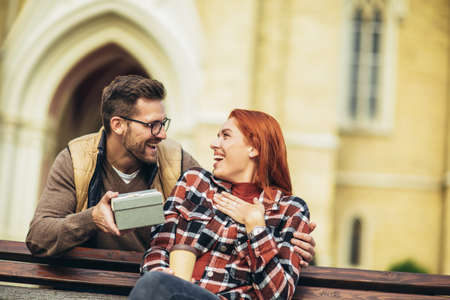 Young couple with present outdoor.Man giving to his woman a gift box.の写真素材
