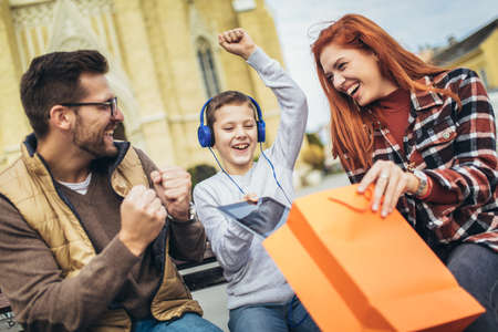 Family sitting on bench, relaxing using gadget, browsing internet.の写真素材
