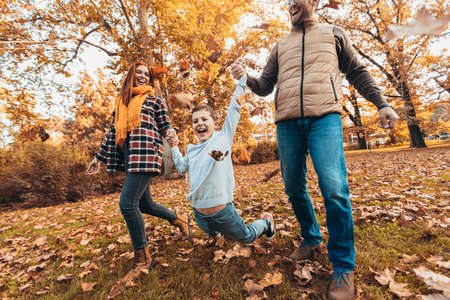 Portrait of a happy family having fun in the autumn park.の写真素材