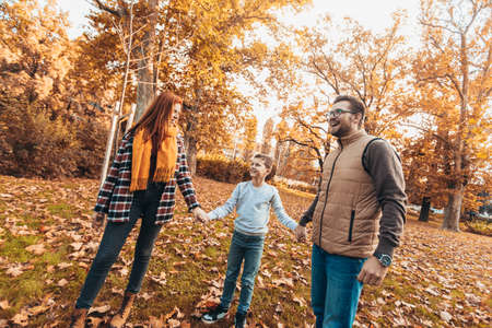 Portrait of a happy family having fun in the autumn park.の写真素材