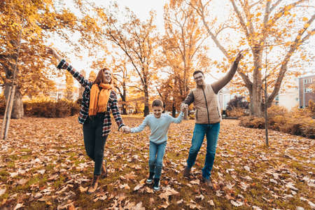 Portrait of a happy family having fun in the autumn park.の写真素材