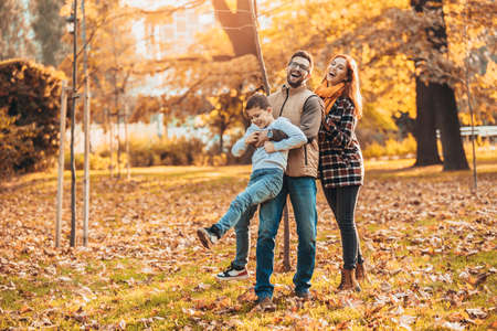 Portrait of a happy family having fun in the autumn park.の写真素材