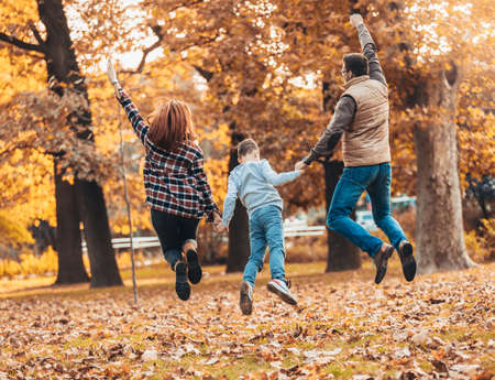Portrait of a happy family having fun in the autumn park.の写真素材