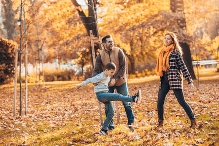 Portrait of a happy family having fun in the autumn park.の写真素材