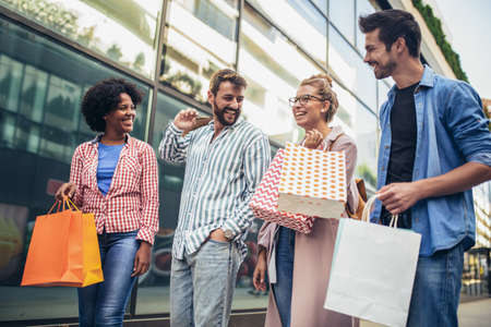 Group of friends walking along street with shopping bags and having fun.の写真素材