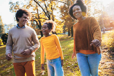 Adorable mixed race family walking in the autumn parkの写真素材