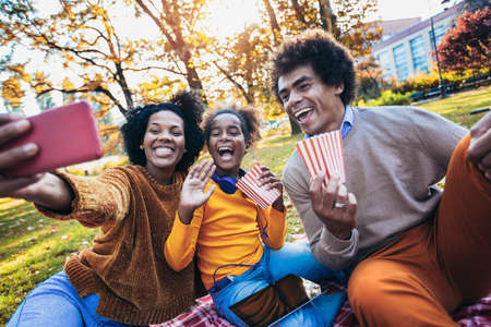 Mixed family having fun while picnicking in the park make selfie photo.の写真素材