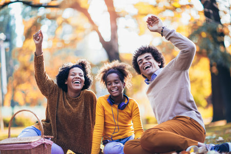 Mixed family having fun while picnicking in the parkの写真素材