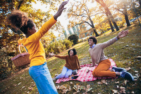 Mixed family having fun while picnicking in the parkの写真素材