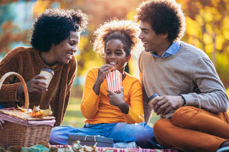 Mixed family having fun while picnicking in the park eating pop corn.の写真素材
