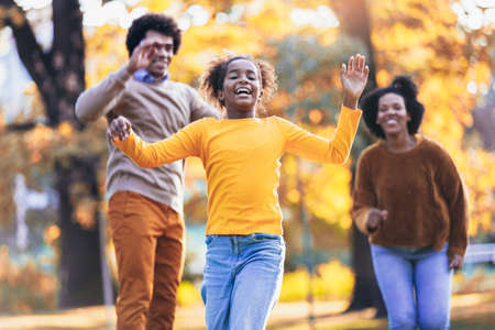 Adorable mixed race family walking in the autumn parkの写真素材