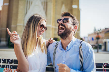 Portrait of beautiful smiling young couple sitting on a bench after shopping.の写真素材