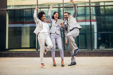 Business team celebrating a triumph, looking at digital tablet.の写真素材