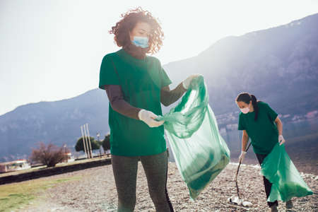 Young female volunteers collecting plastic garbage at beachの写真素材
