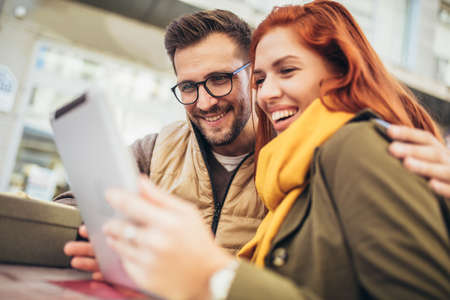 Trendy young couple in town using tablet