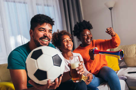 Excited family watching football match at home