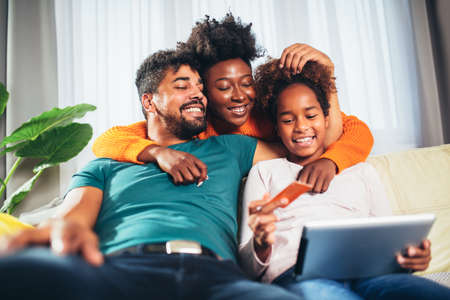 Online Shopping. Happy african family having fun using credit card and digital tablet at home.の写真素材