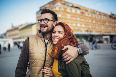 Smiling couple enjoying on vacation, young tourist having fun walking and exploring city street during the day.の写真素材